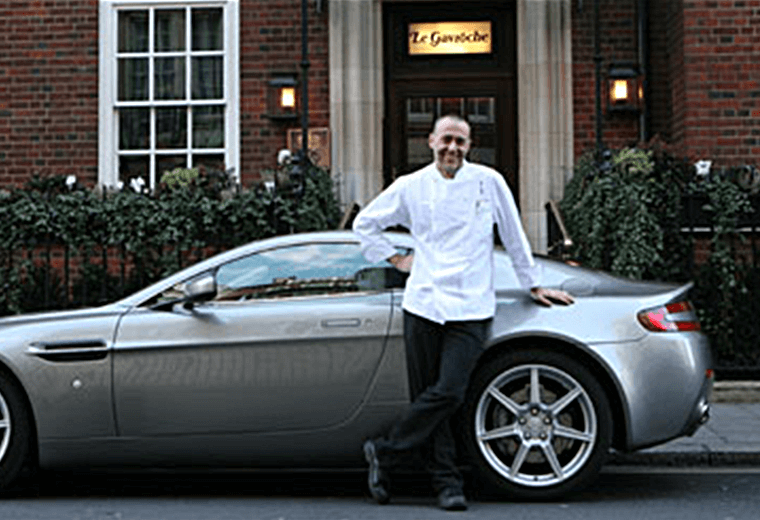Michel Roux posing outside his restaurant Le Gavroche with a sports car
