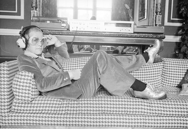 Elton John reclining on a sofa