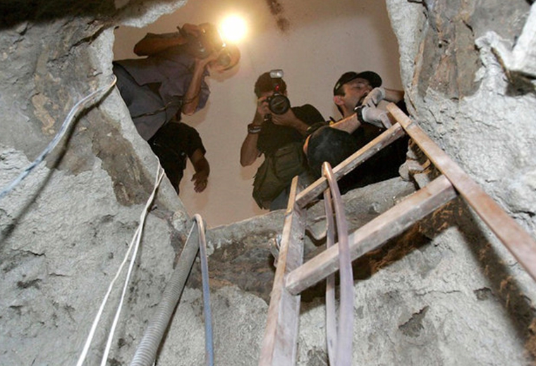 Men peering down a hole made for a bank raid in Brazil