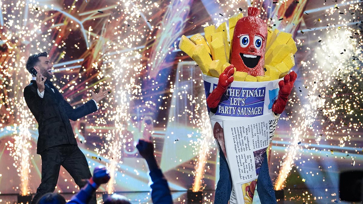 The Masked Singer host Joel Dommett celebrates with series winner Sausage