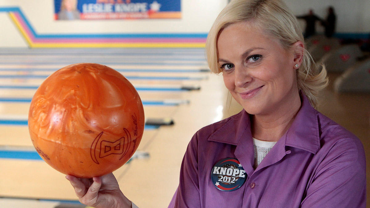 Leslie Knope (Amy Poehler) from Parks And Recreation holding a bowling ball...